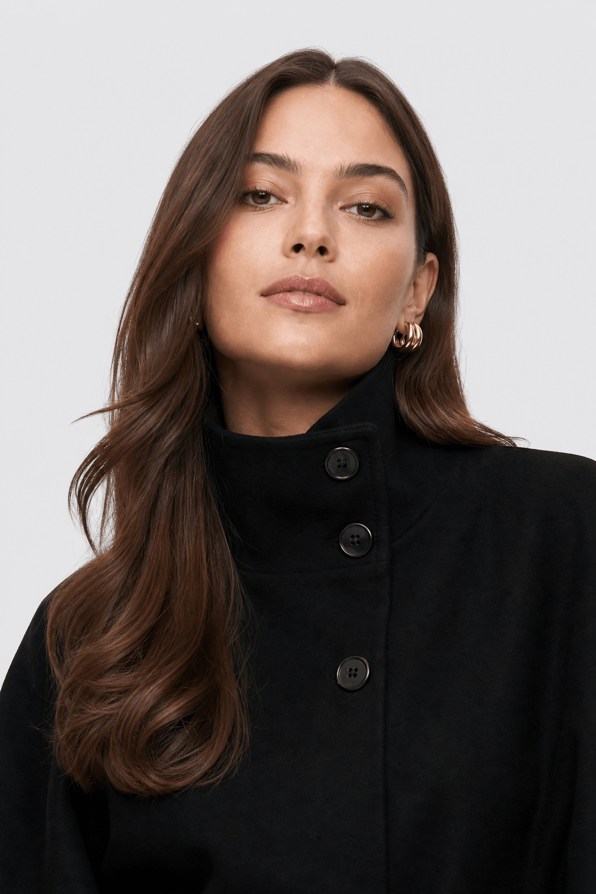 Cape veste noire courte à col montant, pans évasés jusqu'aux hanches et ceinture fine